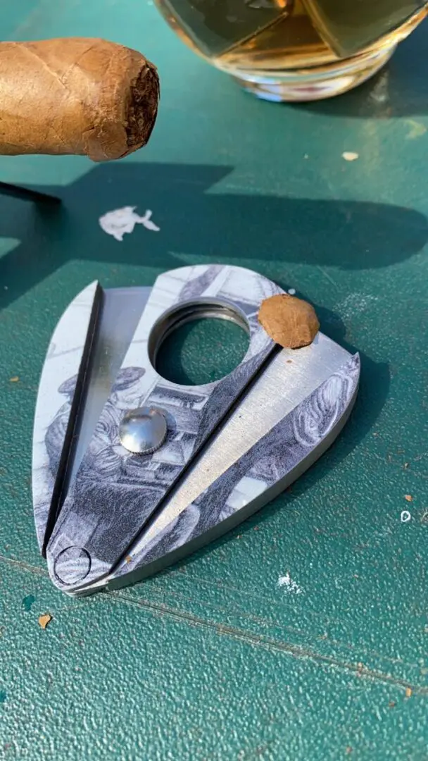 Silver cigar cutter with a design.