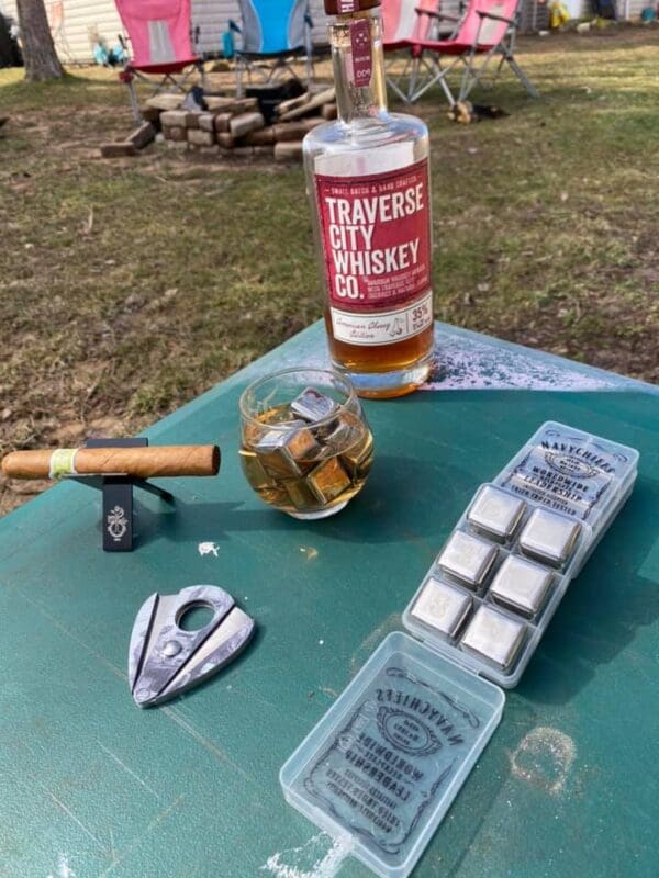 Whiskey bottle with ice cubes and cigar cutter.