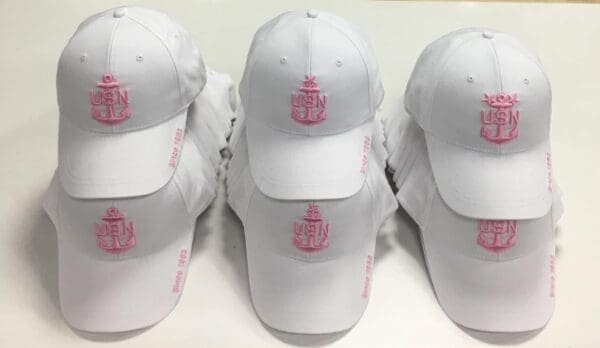 A group of white hats with pink logo on them.