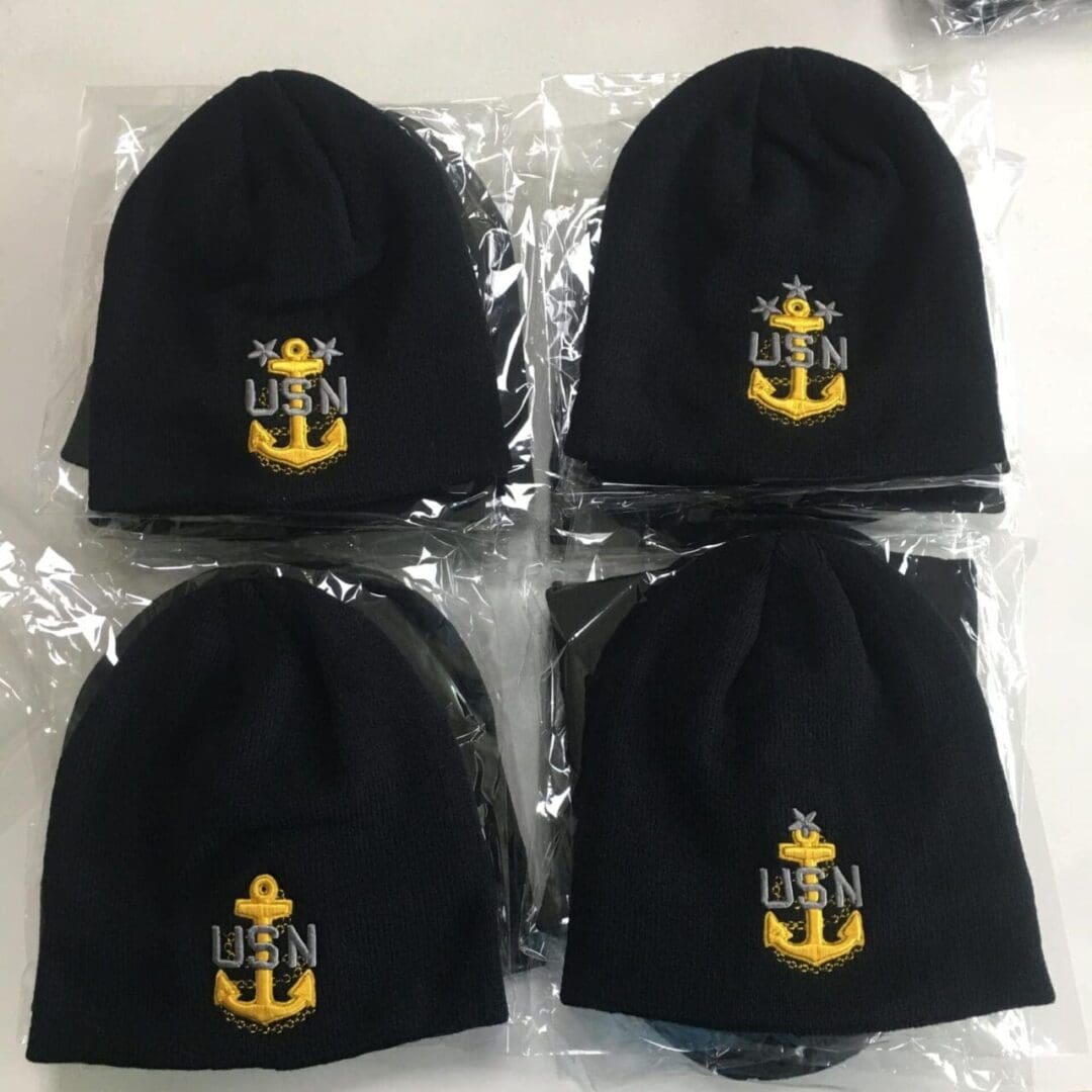 A set of four black hats with yellow anchors on them.