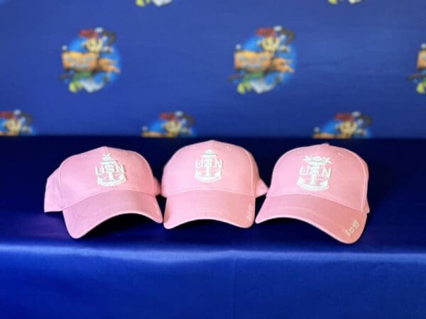 Three pink hats are sitting on a blue bench.