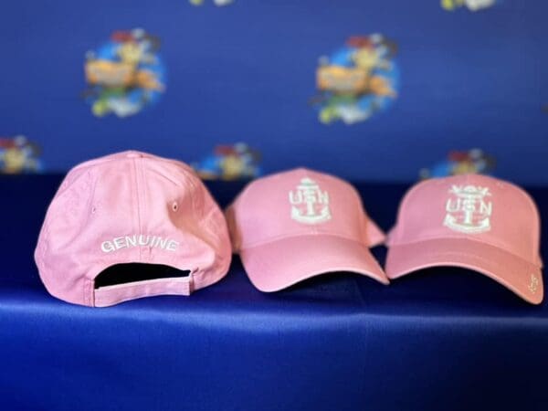 Three pink hats are sitting on a blue bench.