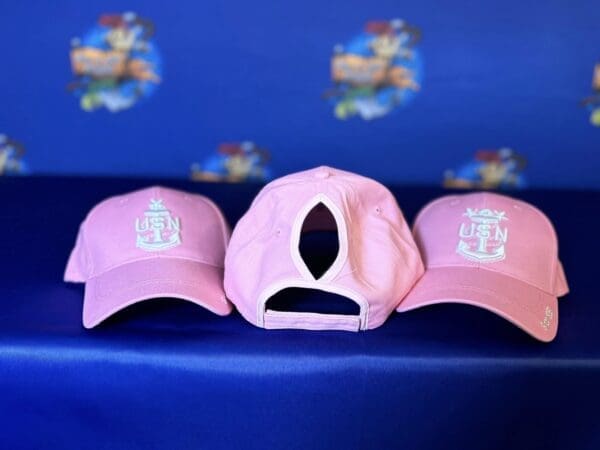 Three pink hats sitting on a blue couch.